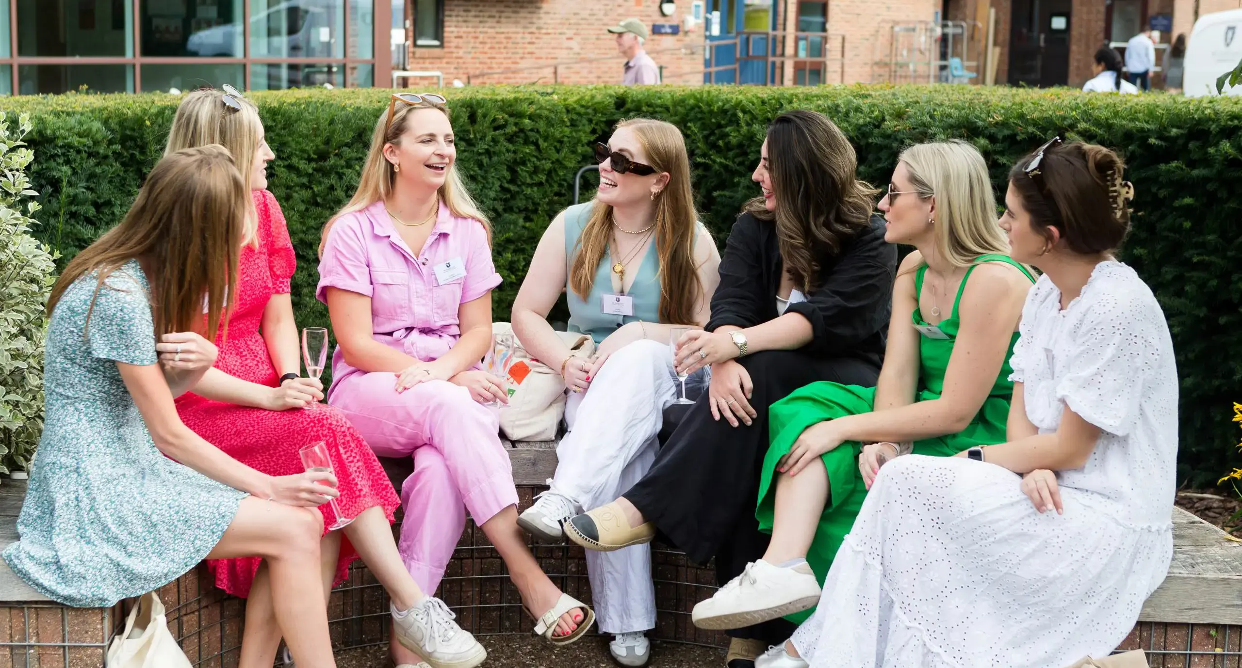 St Swithun's alumnae sitting on a brick wall and chatting