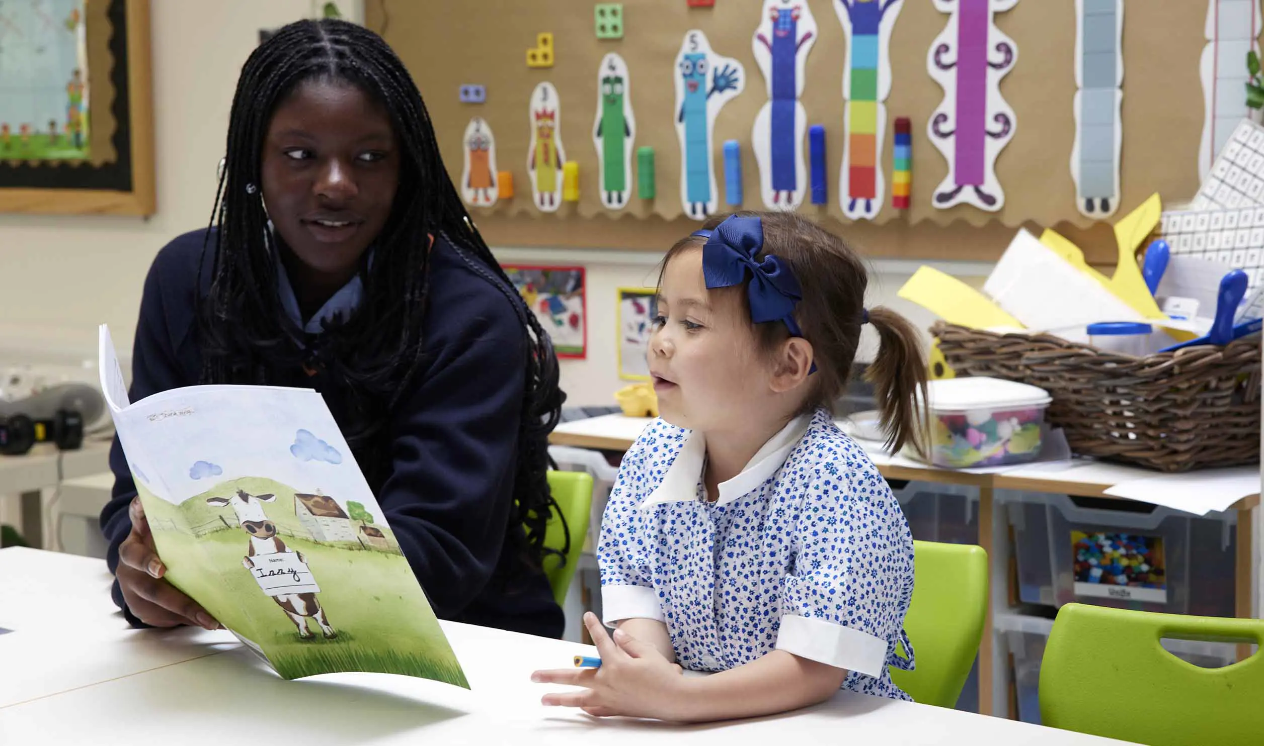 Black female student and younger student reading together at school