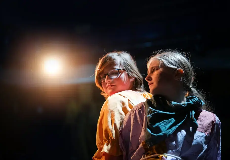 Two students standing back to back in a drama performance