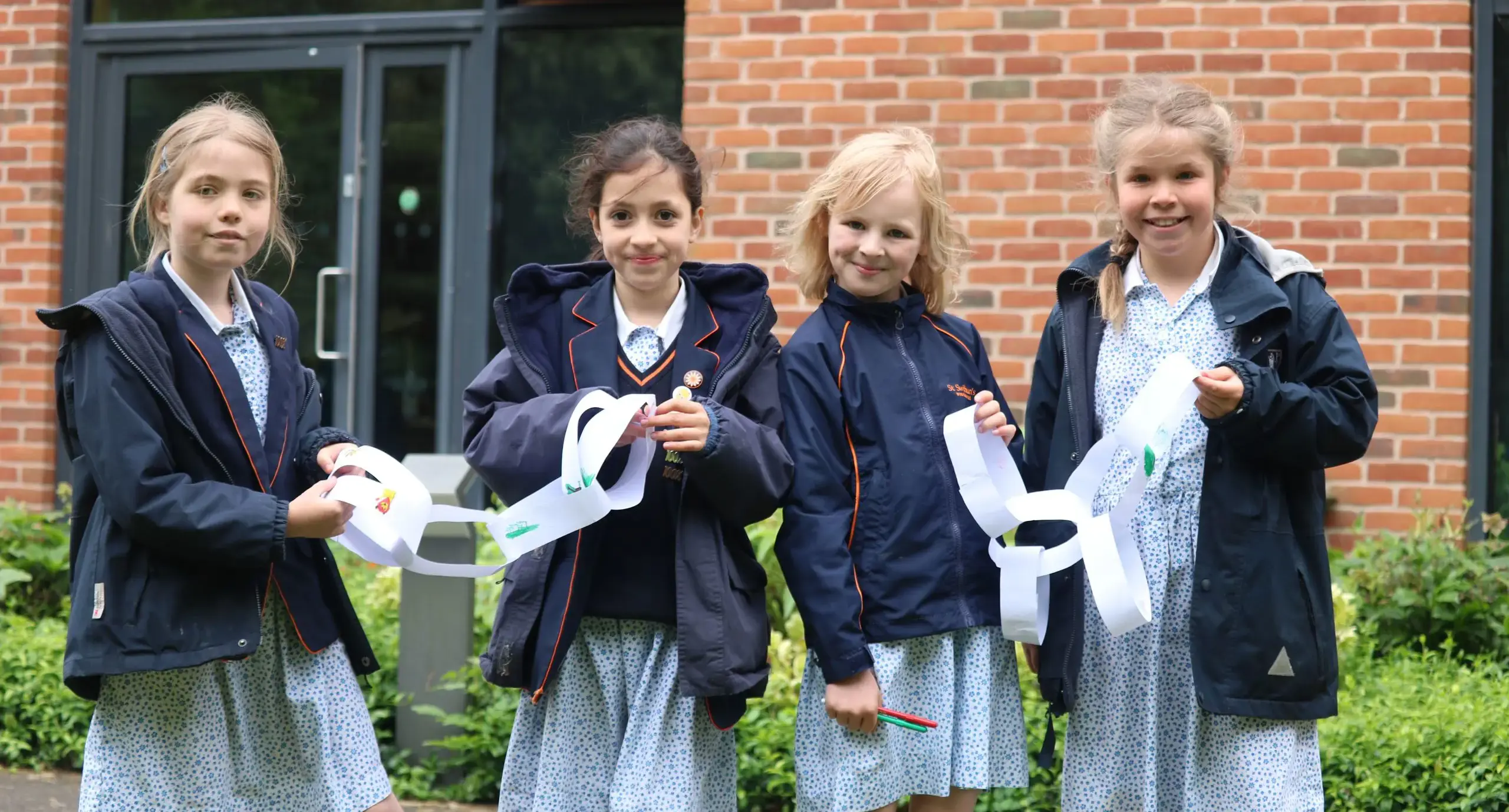 Four students holding paper daisy chains