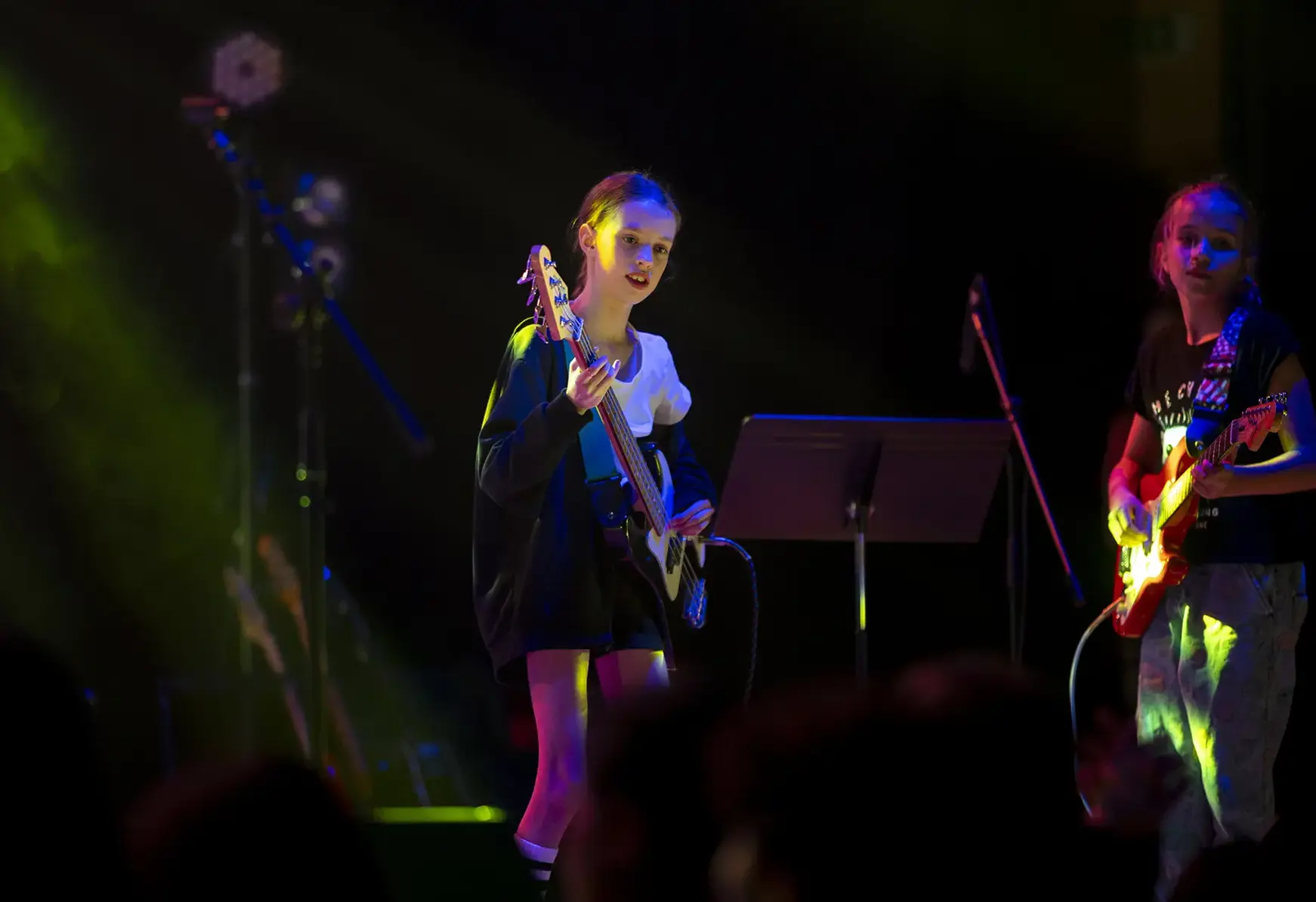 Student playing guitar on stage young girl